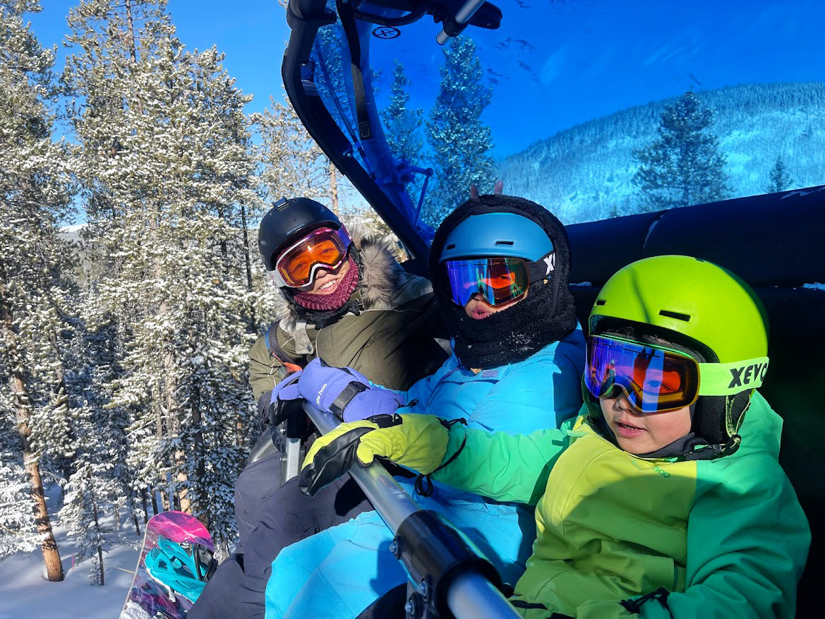 A mom and 2 kids on a chair lift